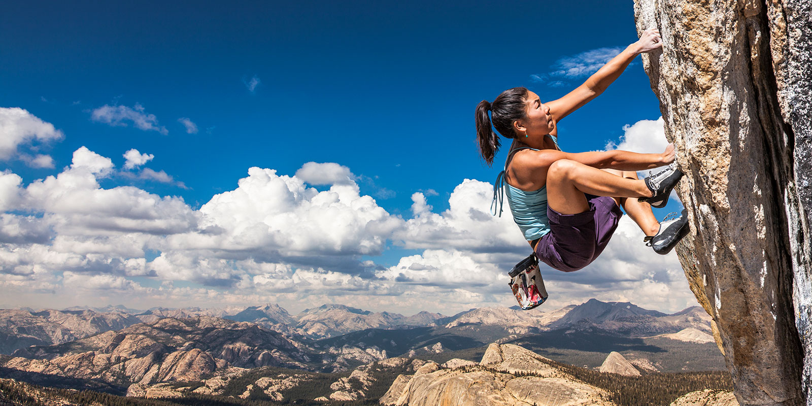 woman climbing a steep mountain rock face