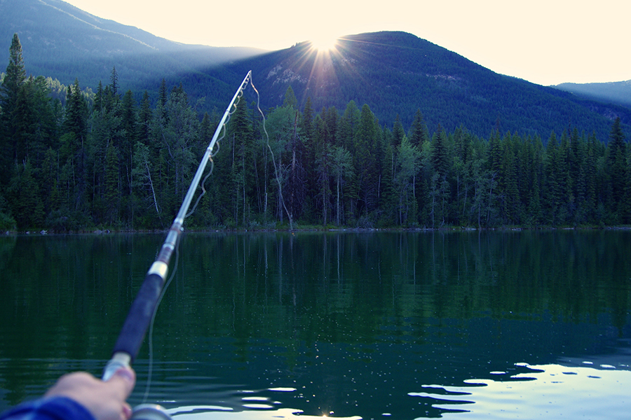 hand holding fishing rod at mountain lake