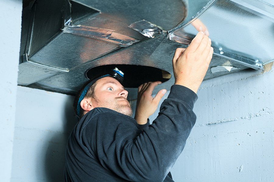 man looking into furnace duct