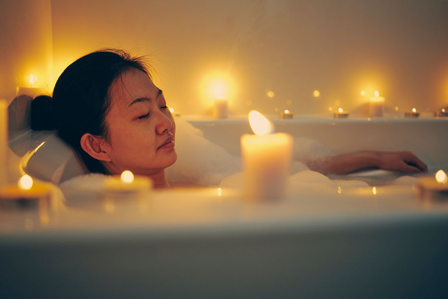 woman relaxing in bathtub with candles