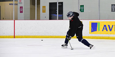 A young minor hockey player takes a slapshot with a Raven Hockey stick