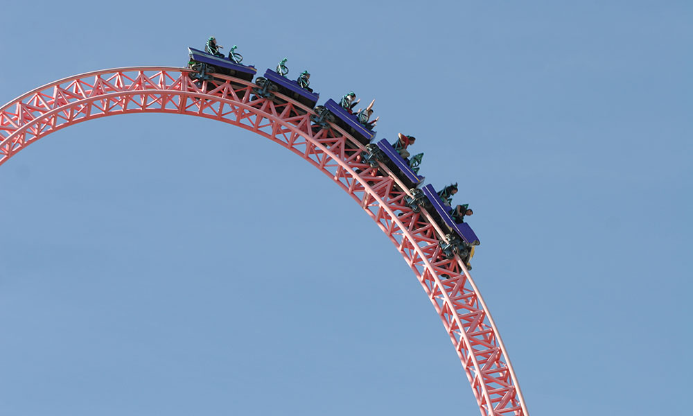 people on roller coaster at top of a hill