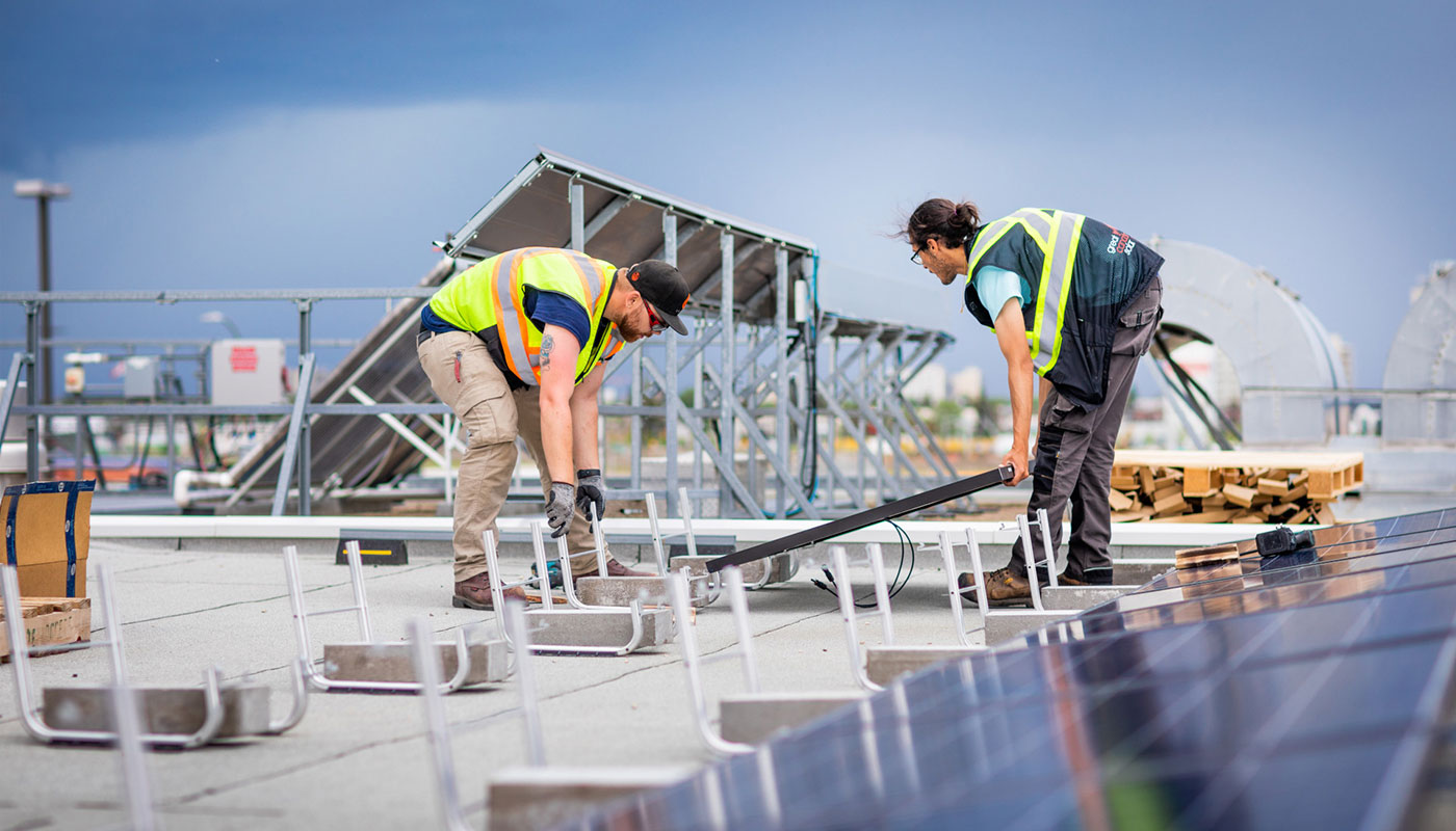 technicians install solar panel on roof of NAIT