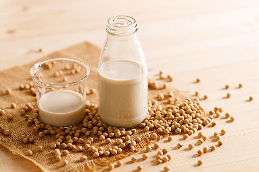 soy milk in a bottle and glass among soybeans on  burlap