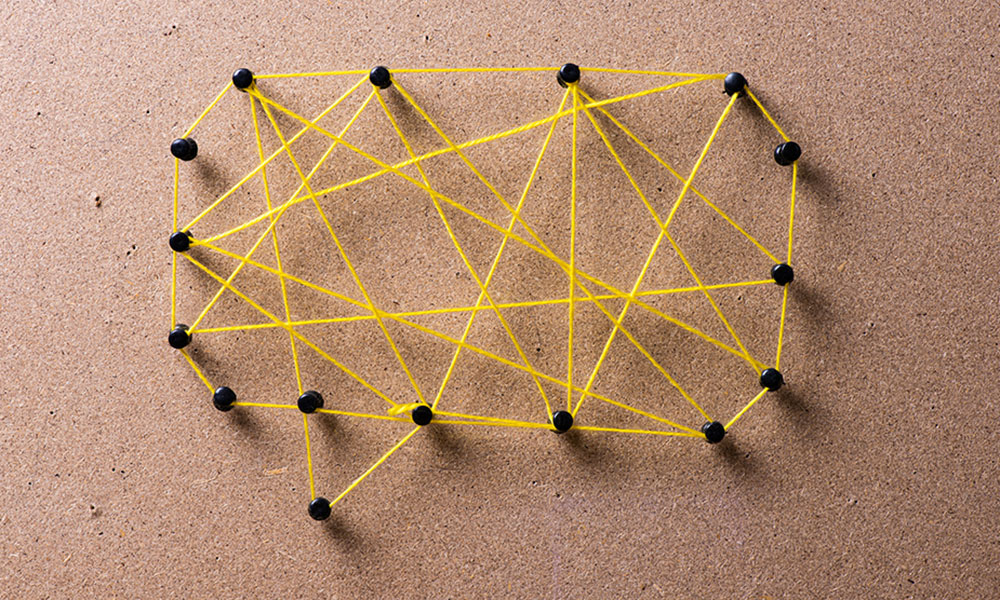 yellow threads on pins arranged into shape of a speech bubble