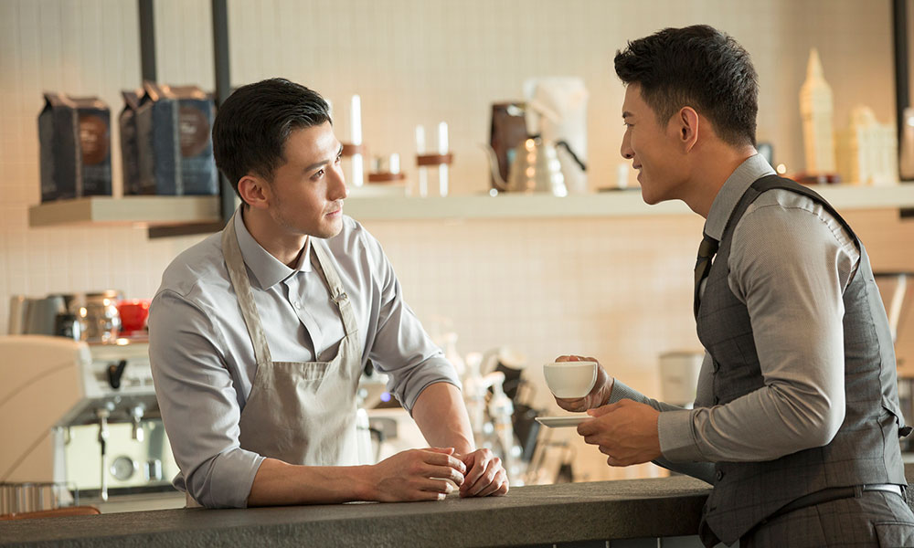 two men having a conversation in a cafe over the counter